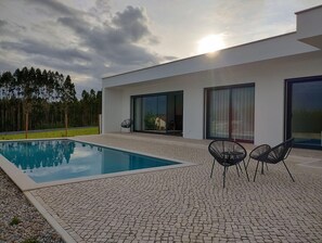 Uma casa moderna com piscina, área de estar externa e grandes janelas.