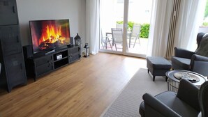 A living room with a fireplace, a television, and a view of the outdoors through a sliding glass door. - Holiday Apartment sea bay (Sassnitz)