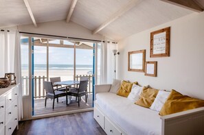 Une chambre avec un lit, une table entourée de chaises, une vue sur la plage et un plafond en bois.