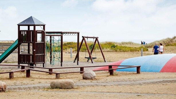 Ein Spielplatz mit Klettergerüst, Schaukeln und Rutsche.