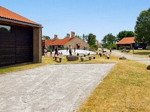 A courtyard with picnic tables, a playground, and a building with a red-tiled roof. - 6 Person Holiday Park Home in Saeby (Sæby)