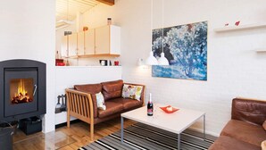 Ein gemütliches Wohnzimmer mit Kamin, einem braunen Ledersofa, einem weißen Couchtisch und einem Streifen Teppich.