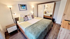Une chambre à coucher comprenant un lit, des tables de chevet, une commode, un miroir et une armoire.