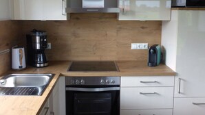 Una cocina moderna con estufa de acero inoxidable, horno empotrado, cafetera y microondas sobre la encimera.