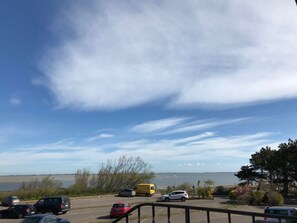 A parking area with vehicles and a view of a body of water. - Holiday Apartment B in Haus Seewind (Wittduen)