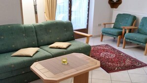 Olohuone, jossa on vihreä sohva, puinen sohvapöytä ja kuviollinen matto.