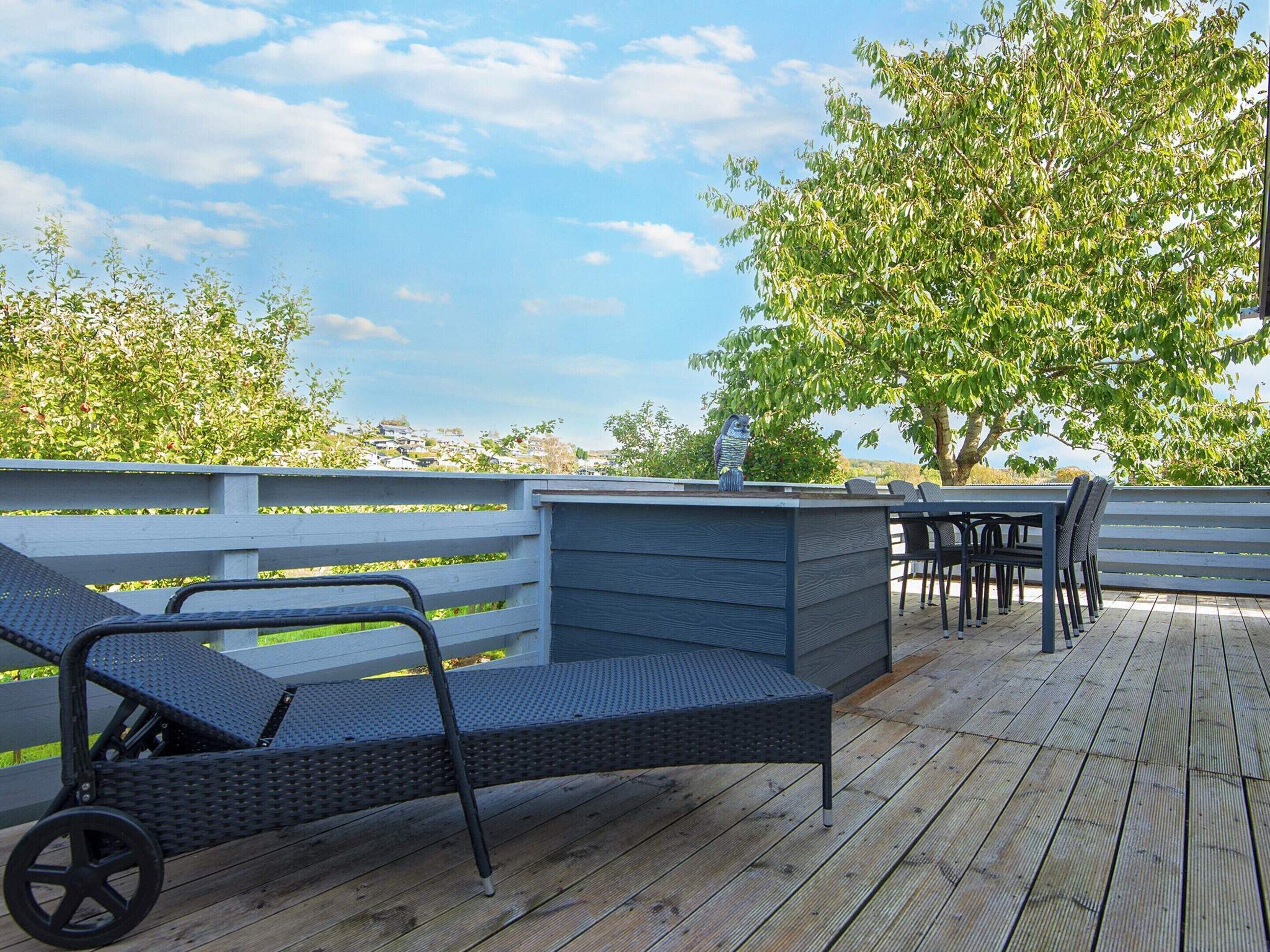 Una terraza al aire libre con zona de estar, que incluye una mesa y sillas, y una estatua decorativa de un búho.