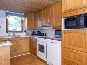 Une cuisine avec des meubles en bois, un four à micro-ondes, une cuisinière et un évier.