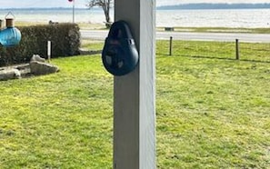 A grassy area with a blue object on a pole, a hedge, and a body of water in the background. - 8 Person Holiday Home in Aabenraa (Aabenraa)