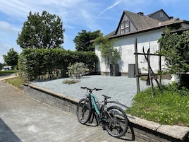 Zona residencial con una casa, un camino de grava y una bicicleta estacionada.