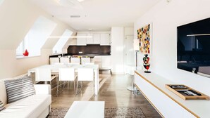 Een moderne woonruimte met een eethoek, keuken en een grote televisie aan de muur.