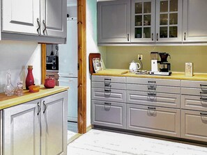 Una cocina con gabinetes grises, encimera de madera y cafetera.