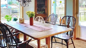 A wooden dining table with chairs, a vase of flowers, and a wine glass. - 4 Star Holiday Home in Onsala (Gottskar)