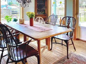 Una mesa de comedor de madera con sillas, un jarrón de flores y una copa de vino.