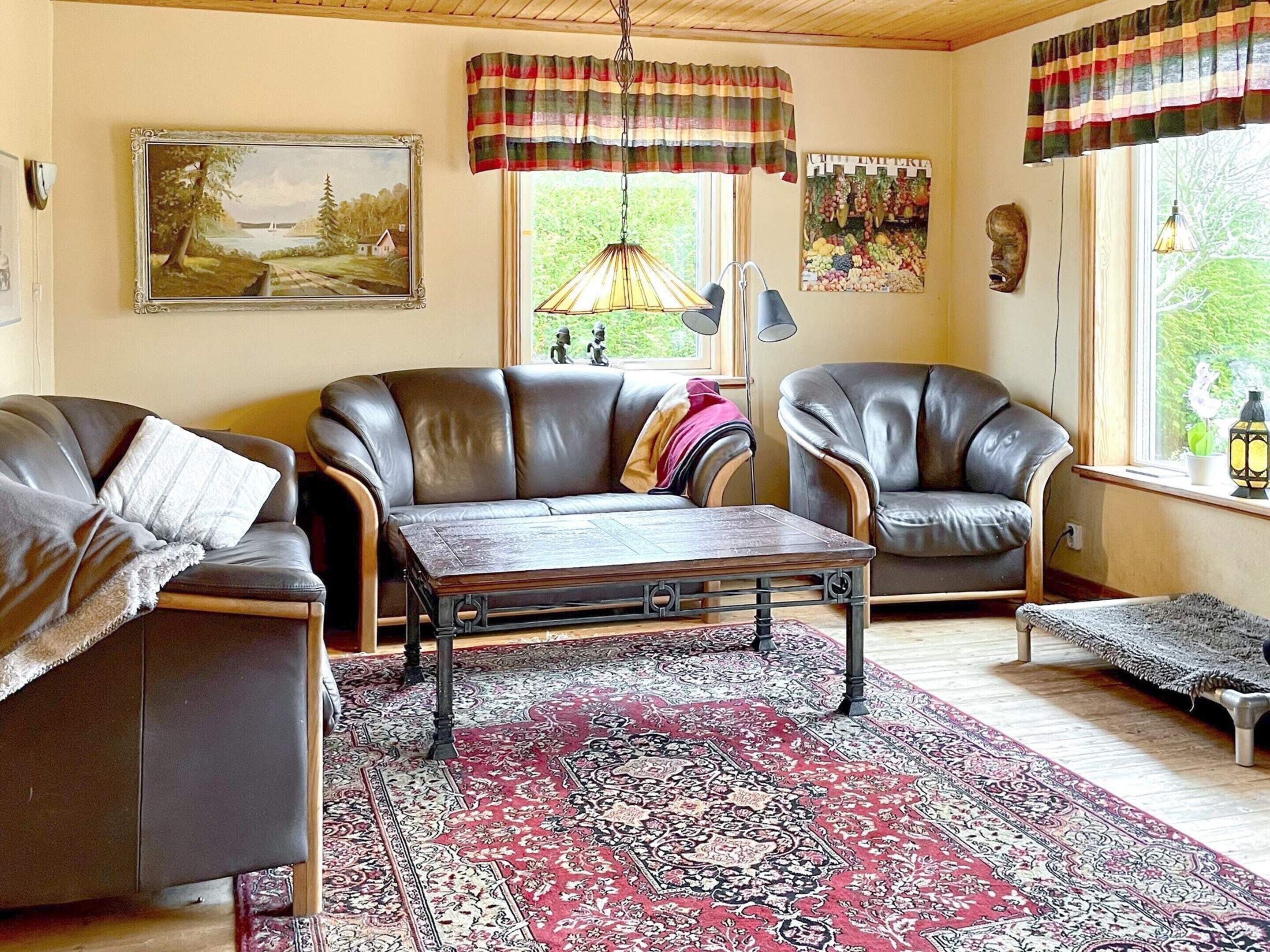 A cozy living room with leather sofas, a patterned rug, and a painting on the wall.