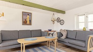 A living room with a grey sofa, a wooden table, a striped rug, and a painting on the wall.