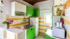 A compact kitchen with green cabinets, a white countertop, a sink, a refrigerator, and a microwave. - Apartment Dorica - Two Bedroom Apartment With Terrace (Dubrovnik)