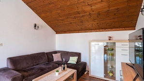 A modern living room with a dark brown sofa, a wooden coffee table, and a glass cabinet with drawers. - Apartment Dorica - Two Bedroom Apartment With Terrace (Dubrovnik)