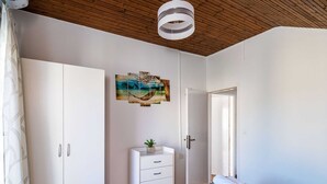 A bedroom with a bed, a wardrobe, a dresser, a painting, and a door. - Apartment Dorica - Two Bedroom Apartment With Terrace (Dubrovnik)