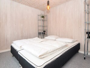 A bedroom with a bed, a metal shelf unit, and a hanging light fixture. - 5 Person Holiday Home in Juelsminde (Horsens)