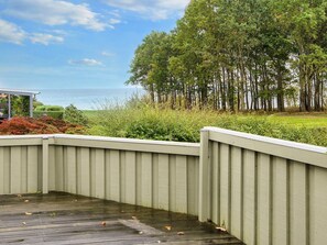 A wooden deck with a railing overlooking a landscaped area with trees and shrubs. - 5 Person Holiday Home in Juelsminde (Horsens)