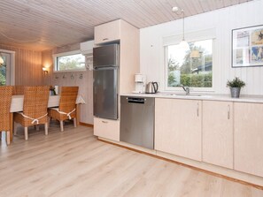 A modern kitchen with a stainless steel refrigerator, dishwasher, and a window with a view of greenery. - 5 Person Holiday Home in Juelsminde (Horsens)