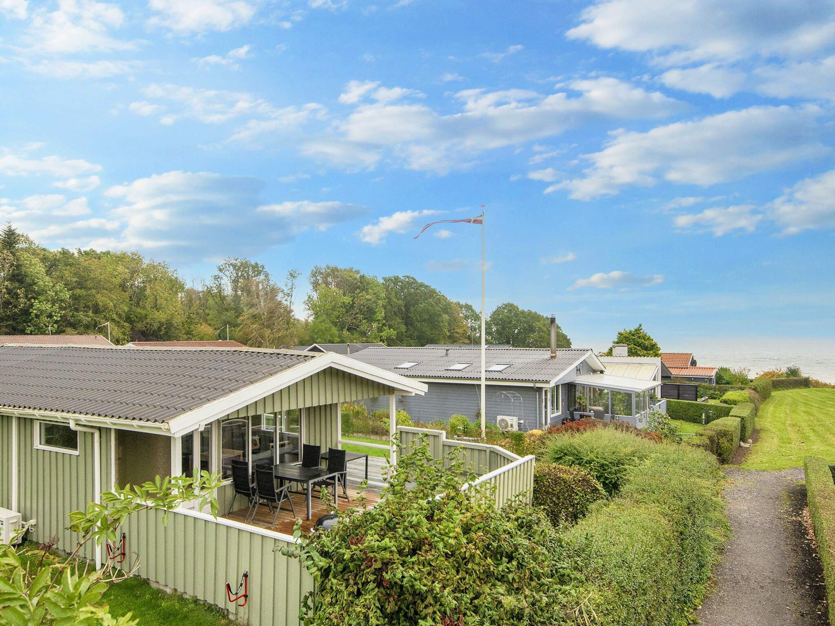 Une rangée de cabanes dotées d’une terrasse, entourées de verdure et baignées par un ciel dégagé.