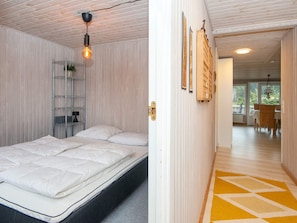 A modern bedroom with a bed, a metal shelving unit, and a hanging light fixture. - 5 Person Holiday Home in Juelsminde (Horsens)