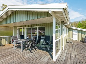 A covered outdoor deck with a table and chairs, a small table, and a door. - 5 Person Holiday Home in Juelsminde (Horsens)