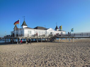Een gebouw aan het strand met een pier, met meerdere vlaggen en een trap naar het bovenste niveau.