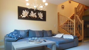Un salon avec un canapé gris, une table basse en bois et un lustre.