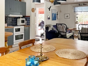 A kitchen with white appliances, a dining table with placemats, and a blue chair. - 6 Person Holiday Home in Blido (Blidö)