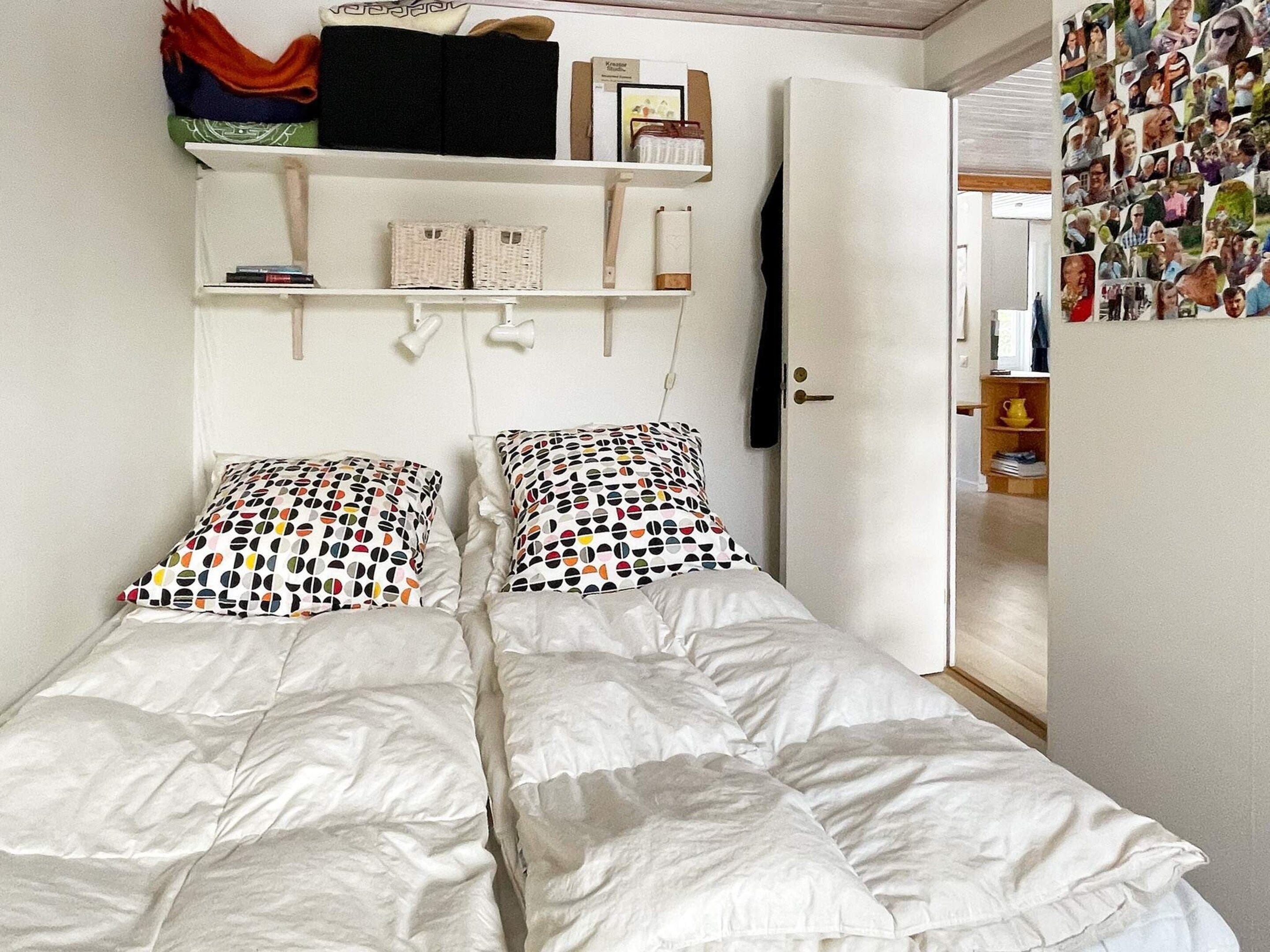 A bedroom with two beds, a wardrobe, and a wall with a collage of photos.