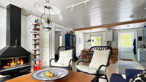A cozy living room with a fireplace, a dining area, and a kitchen. - 6 Person Holiday Home in Blido (Blidö)