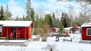 A cluster of red cabins with snow-covered roofs, surrounded by trees and a clear sky. - 6 Person Holiday Home in Blido (Blidö)