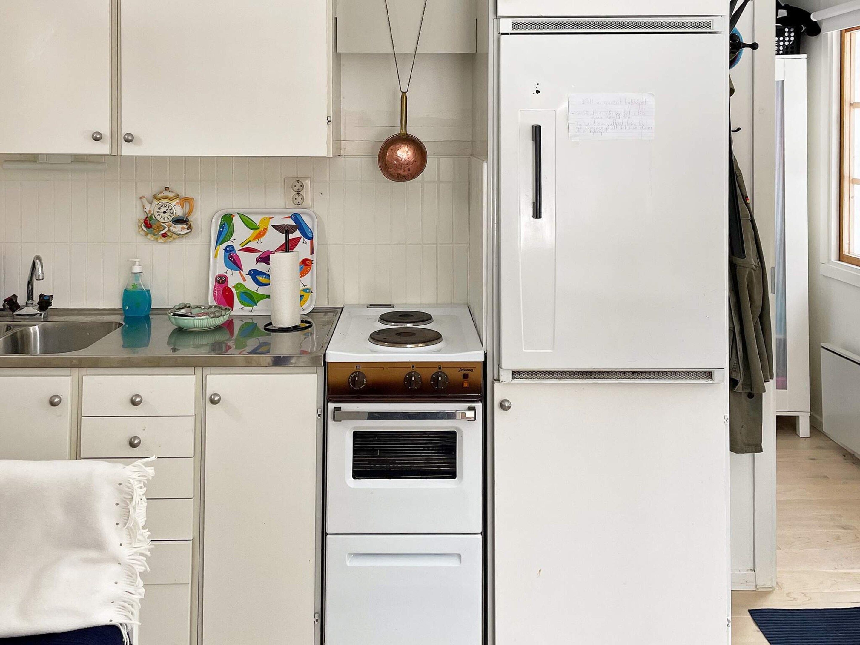 A kitchen with white cabinets, a stove, a refrigerator, and a sink.