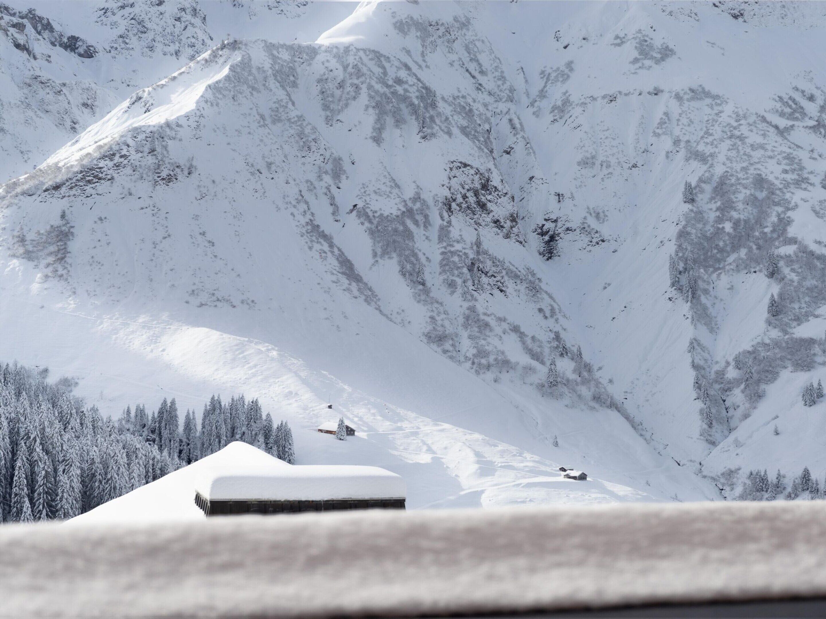 Une montagne enneigée, avec un chalet situé à son pied.