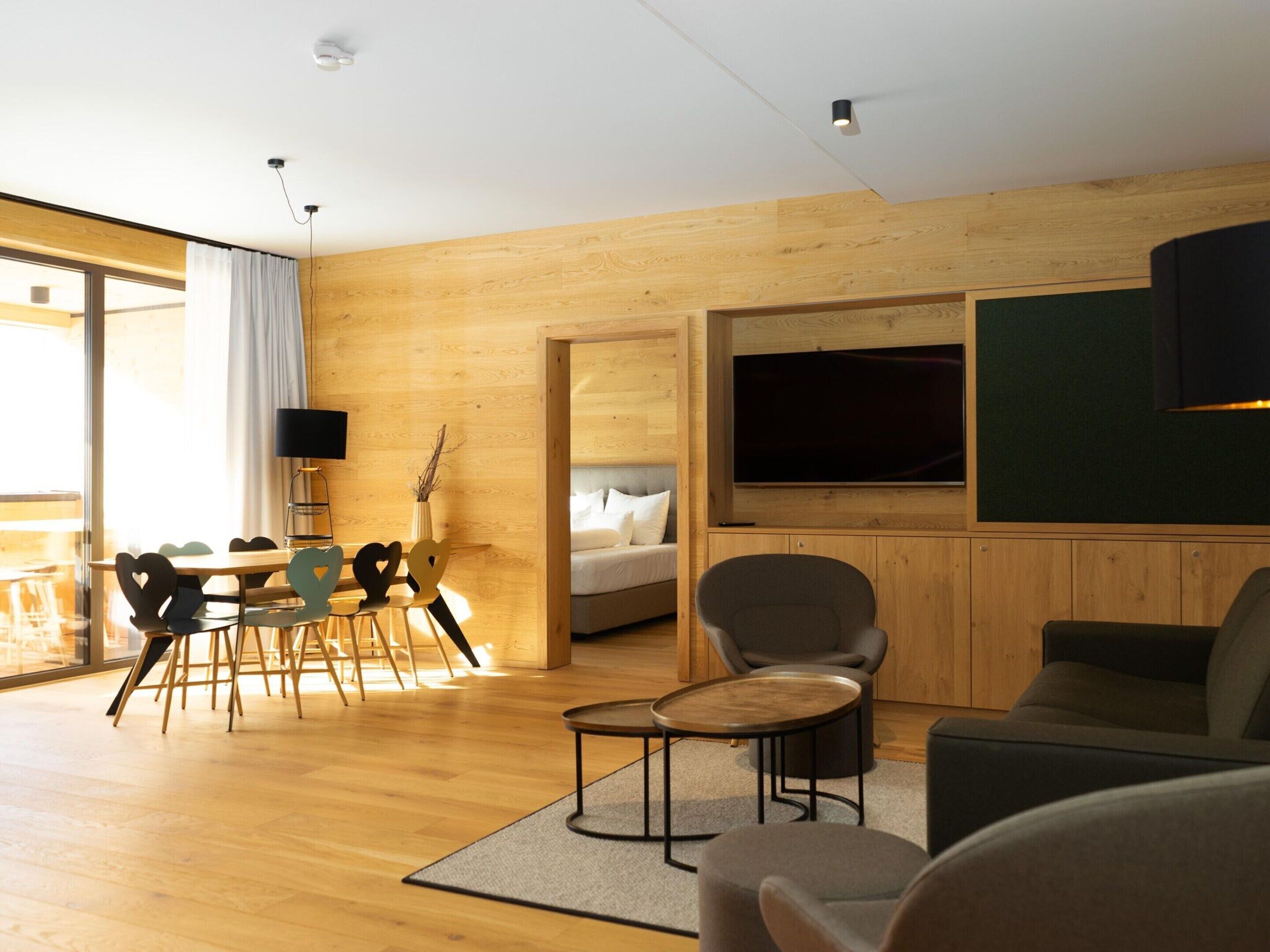 Una sala de estar moderna con piso de madera, un sofá, una mesa de centro y un televisor montado en la pared.