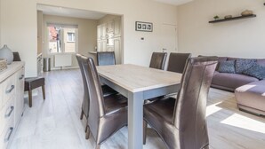 A modern living room with a dining table, leather chairs, a sofa, and a kitchen area in the background. - Bright Apartment in the City Center (Blankenberge)
