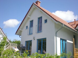 A two-story house with a red-tiled roof, white exterior walls, and blue-framed windows. - Holiday Home Der Schwelmer (Zingst)
