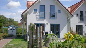 A two-story house with a red-tiled roof, white exterior walls, and blue-framed windows. - Holiday Home Der Schwelmer (Zingst)