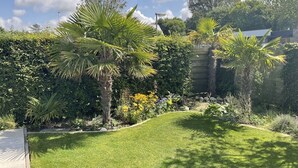 Un jardín cuidado con palmeras, arbustos variados y un césped impecable.