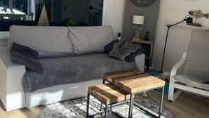 Una sala de estar moderna con un sofá gris, una mesa de centro de madera y una alfombra estampada.