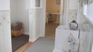 Een badkamer met een douche, een handdoekhouder, een mand en een wastafel.
