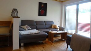 Un salón con un sofá de color gris oscuro, una mesa de centro de madera y un banco de madera.