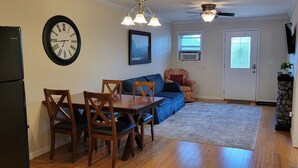 A dining area with a wooden table and chairs, a blue sofa, and a clock on the wall.