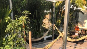 Ein Gartenbereich mit Kübelpflanzen, einer Hängematte und einer Metallkonstruktion.