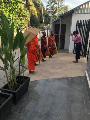 Monks in orange robes carrying alms bowls and a woman in a pink shirt praying. - Siem Reap Homesteading Garden Retreat (Siem Reap)