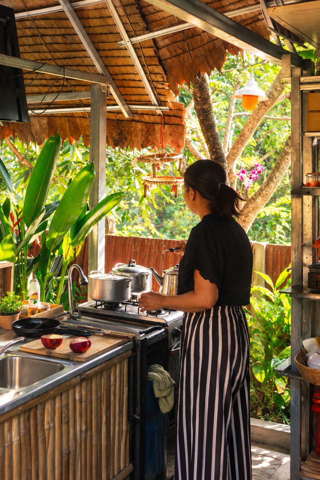 Une personne qui cuisine à l’extérieur, avec une cuisinière à gaz, des casseroles et un évier.