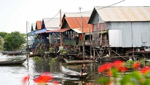 A traditional floating house with a person in a boat. - Siem Reap Homesteading Garden Retreat (Siem Reap)